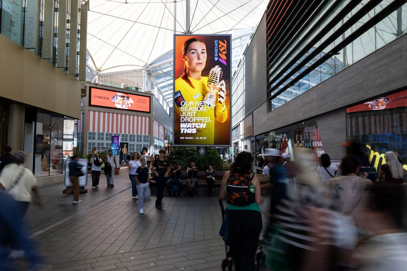 Pantalla Digital Out-of-Home de Barclays Women’s Super League en un centro comercial del Reino Unido con una jugadora y el mensaje Our new season just dropped. Watch this.